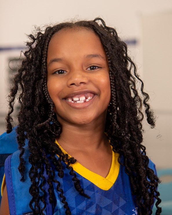 Menina sorrindo, aluna da rede municipal.